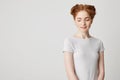 Portrait of shy young pretty redhead girl with buns looking down smiling over white background. Royalty Free Stock Photo