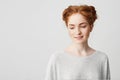 Portrait of shy young pretty redhead girl with buns looking down smiling over white background. Royalty Free Stock Photo