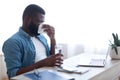 Portrait of sick man blowing his nose with a tissue paper and holding a glass of water at workplace