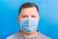 Portrait of a sick man wearing medical mask with what is text at blue background. concept. Protect your Royalty Free Stock Photo