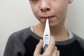 Portrait of sick sad boy child with thermometer having fever suffering from measles or chicken pox with bumps all over face. Royalty Free Stock Photo