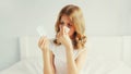Portrait of sick upset woman sneezing blow nose using tissue and looking at the pills, female patient does not want to take