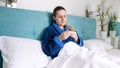 Portrait of young sick woman lying in bed and looking at thermometer Royalty Free Stock Photo