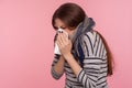 Portrait of sick woman wrapped in warm scarf sneezing in napkin, cleaning nose, suffering allergy or flu symptoms