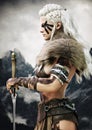 Portrait side view of a fierce viking female warrior with white braided hair and black face paint markings.