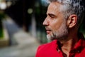 Portrait, side view of mature businessman in red shirt standing on street. Royalty Free Stock Photo