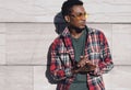 Portrait side view of stylish african man wearing sunglasses, red plaid shirt, guy looking away posing on city street Royalty Free Stock Photo