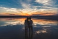 Portrait, silhouette of happy couple watching the colourful bright sunset standing in large lake and kissing, reflection in the wa Royalty Free Stock Photo