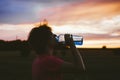 Portrait of a silhouette of a young tourist woman drinking water from a transparent blue bottle in a field, jars at sunset. The gi Royalty Free Stock Photo