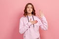 Portrait of sincere honest teen girl in hoodie holding hand up and on chest, pledging allegiance Royalty Free Stock Photo