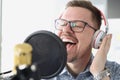 Portrait of singing young man in headphones front of microphone in studio Royalty Free Stock Photo