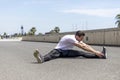 Portrait of sitting runner outside doing stretch in street Royalty Free Stock Photo