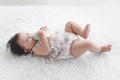 Portrait of six months crawling baby holding milk bottle on fluffy white rug, happy smiling adorable sweet little girl kid lying Royalty Free Stock Photo