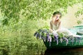 Portrait of slavic or baltic woman with wreath sitting in boat with flowers. Summer Royalty Free Stock Photo