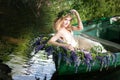 Portrait of slavic or baltic woman with wreath sitting in boat with flowers. Summer Royalty Free Stock Photo