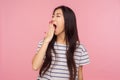 Portrait of sleepy exhausted girl with brunette hair in striped t-shirt yawning and covering mouth with hand