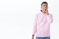 Portrait of sleepy handsome blond man in pink hoodie, close eyes and yawning over fatigue, tired of working late, waking Royalty Free Stock Photo