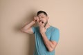 Portrait of sleepy man yawning on beige background