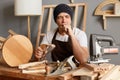 Portrait of sleepy tired exhausted young joiner wearing apron and cap working in workshop long hours, yawning, looks sleepy, Royalty Free Stock Photo