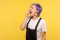 Portrait of sleepy tired hipster woman yawning and closing mouth with hand. yellow background, studio shot