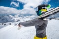 Portrait of a slender skier sportswoman in a cap, mask on her face and ski goggles, mask with skis on her shoulders