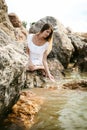 Portrait of slender young woman on stones near the sea Royalty Free Stock Photo