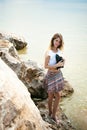 Portrait of slender young woman on stones near the sea Royalty Free Stock Photo