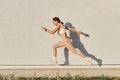 Portrait of slim sporty female wearing white top and beige leggins running over in the air, having energy, work out  on Royalty Free Stock Photo