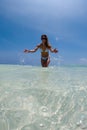 Portrait of a slim woman splashing water on the beach in a bikini. Royalty Free Stock Photo