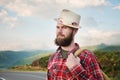 Portrait of a sly cheerful bearded Jewish man hitchhiker in a hat and shirt against the backdrop of a suburban landscape