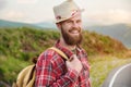 Portrait of a sly cheerful bearded Jewish man hitchhiker in a hat and shirt against the backdrop of a suburban landscape