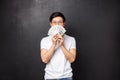 Portrait of sly happy and pleased asian young man winning big cash prize money, hiding face behind fan of dollars