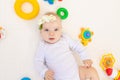 Portrait of a small baby girl 6 months old lying on her back on a white bed at home among toys, top view Royalty Free Stock Photo