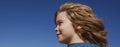 Portrait of a small blond boy looking away on blue sky with copy space, closeup banner. Cute kids face. Positive Royalty Free Stock Photo