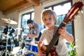 Portrait of small boy with father indoors at home, playing drums and guitar. Royalty Free Stock Photo