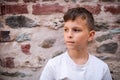 A portrait of small boy standing outdoors in front of old brick wall. Royalty Free Stock Photo
