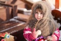 Portrait of a small brown-eyed girl in a rustic style. The baby is sitting on a wooden porch, in her hands she holds a wicker bask Royalty Free Stock Photo