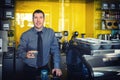 Portrait of small business owner smiling and standing behind counter inside coffee shop holding cup of coffee Royalty Free Stock Photo