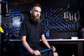 Portrait of small business owner of young man with beard. Guy bicycle mechanic workshop worker sitting with tool in his hand in a Royalty Free Stock Photo