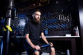 Portrait of small business owner of young man with beard. Guy bicycle mechanic workshop worker sitting with tool in his hand in a Royalty Free Stock Photo