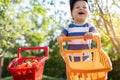 Portrait of small caucasian cute blond toddler boy holding toy shopping cart full of sweet ripe apricots against green Royalty Free Stock Photo