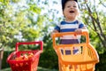 Portrait of small caucasian cute blond toddler boy holding toy shopping cart full of sweet ripe apricots against green Royalty Free Stock Photo