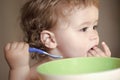 Portrait of small child baby eating from plate with hand holding spoon closeup. Royalty Free Stock Photo