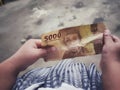 Small child arm holding a piece of money with a camera view from above