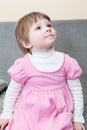 Portrait of small four years old girl in pink dress sitting on sofa and looking Royalty Free Stock Photo