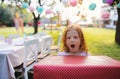 Portrait of small girl with large present box outdoors in garden in summer.