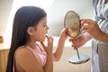 Small girl with mother in bathroom indoors, looking in mirror at baby loose tooth.