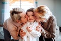 A portrait of small girl with mother and grandmother at home, kissing.