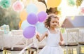 Portrait of small girl playing with balloons outdoors on garden party in summer. Royalty Free Stock Photo