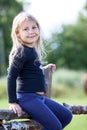 Portrait of small girl sitting on village fence